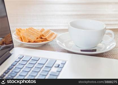 Laptop with coffee cup and snack, stock photo
