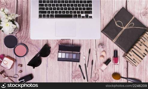 laptop with cosmetics products diary pink wooden textured backdrop