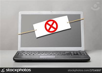 laptop with deny sign on gray background