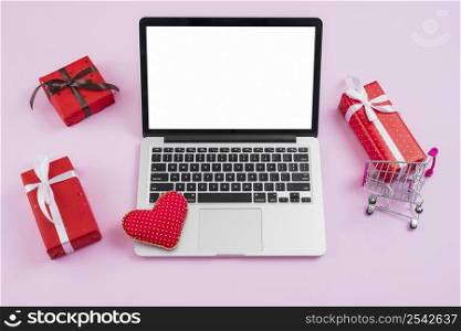 laptop with handmade heart amidst gifts shopping cart