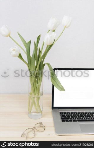 laptop with white tulips vase table