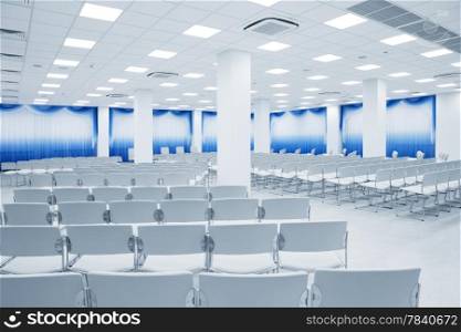 large and modern white auditorium with blue curtains