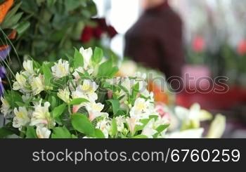 Large array of flowers in florist shop, in the background female customer out of focus