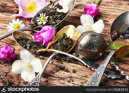 large assortment of herbal teas in tea-spoons on a wooden background. Tea spoons with tea leaves