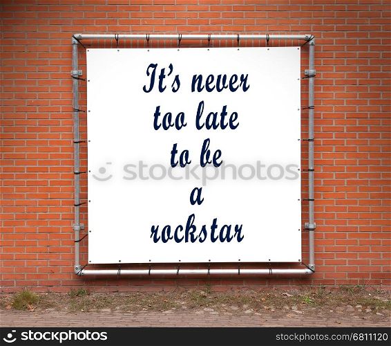 Large banner with inspirational quote on a brick wall - It's never too late to be a rockstar