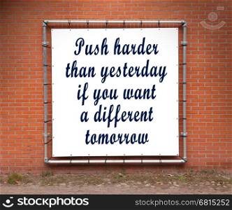 Large banner with inspirational quote on a brick wall - Push harder than yesterday...