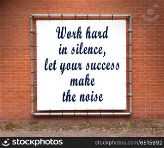 Large banner with inspirational quote on a brick wall - Work hard in silence...
