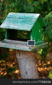 large birdhouse in a forest and a blackboard