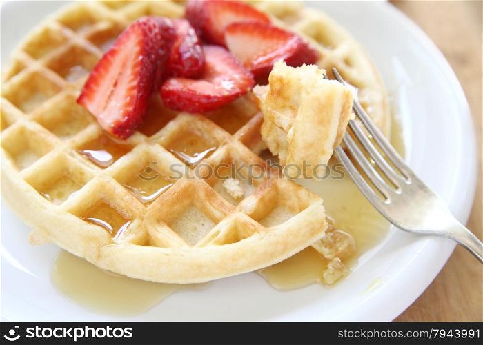 large breakfast waffle with fresh strawberries and syrup
