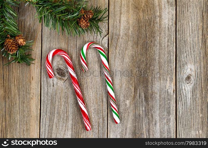 Large candy canes with evergreen setting on rustic wood. High angled view in horizontal format.