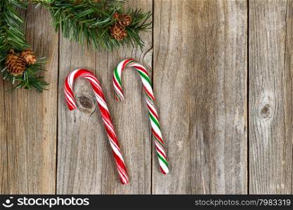 Large candy canes with evergreen setting on rustic wood. High angled view in horizontal format.