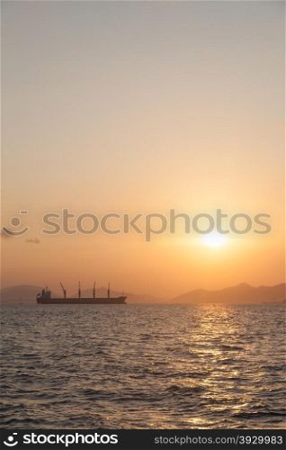 Large cargo ship In the morning the sun rises Ship moored in the sea