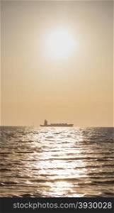 Large cargo ship In the morning the sun rises Ship moored in the sea