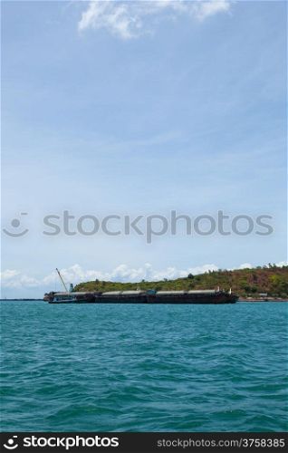 Large cargo ship. Moored at sea. Island near the docks.