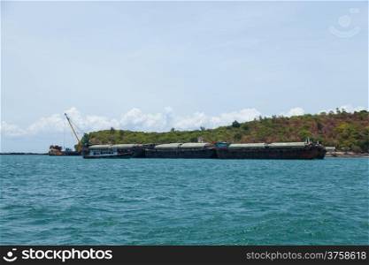 Large cargo ship. Moored at sea. Island near the docks.