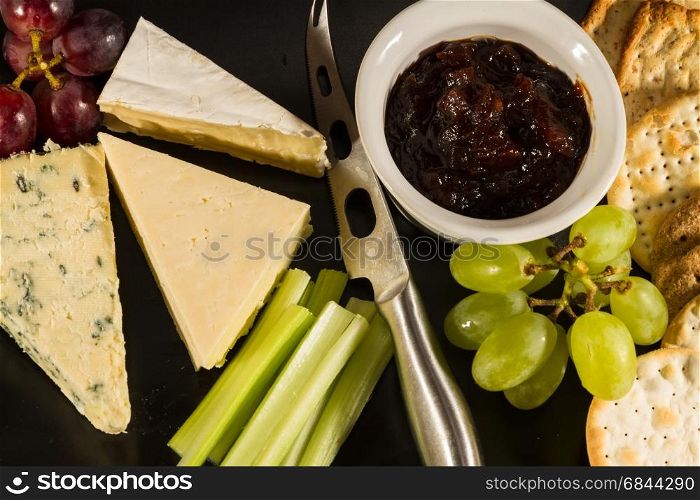 Large cheeseboard with brie, cheddar, stilton, grapes, red onion chutney, celery and crackers.