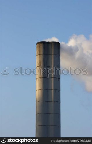 Large chimney sent clouds of steam into the blue sky