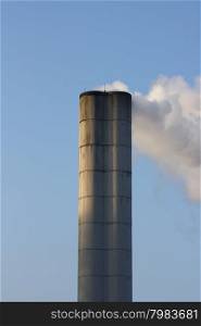 Large chimney sent clouds of steam into the blue sky