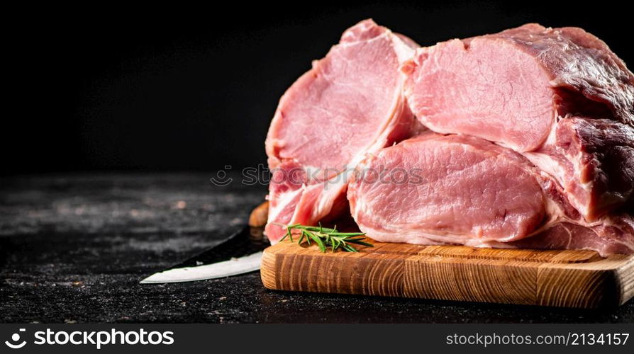 Large chunks of raw pork on a wooden cutting board. On a black background. High quality photo. Large chunks of raw pork on a wooden cutting board.