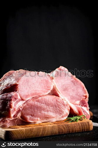 Large chunks of raw pork on a wooden cutting board. On a black background. High quality photo. Large chunks of raw pork on a wooden cutting board.