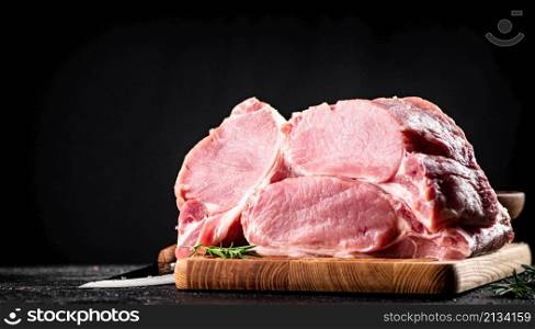 Large chunks of raw pork on a wooden cutting board. On a black background. High quality photo. Large chunks of raw pork on a wooden cutting board.