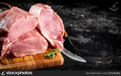 Large chunks of raw pork on a wooden cutting board. On a black background. High quality photo. Large chunks of raw pork on a wooden cutting board.