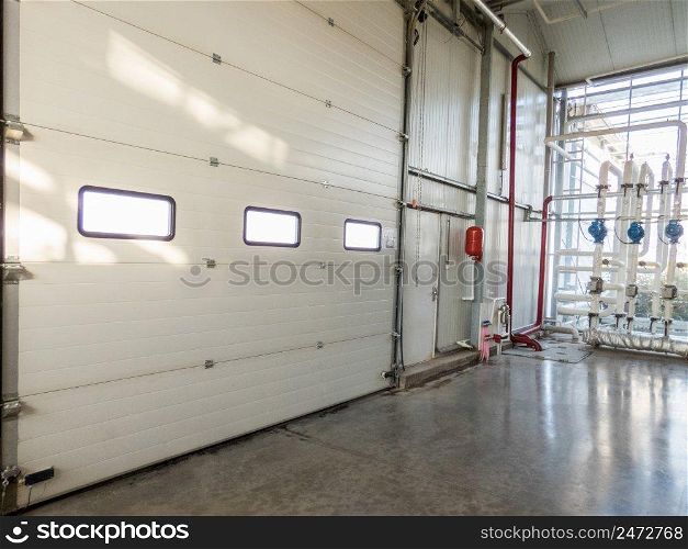 large closed gate with windows in the factory. pipes and motor. big door at the factory