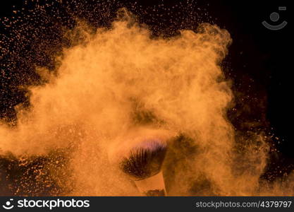 large cloud orange powder around makeup brush dark background