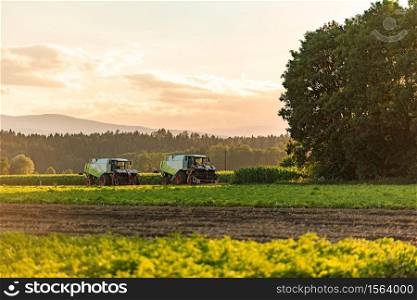 Large combine harvesters standing in agricultural field at summertime after day work.. Large combine harvesters standing in agricultural field at summertime.