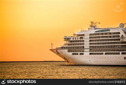 large cruise liner ship going from port with sunset background