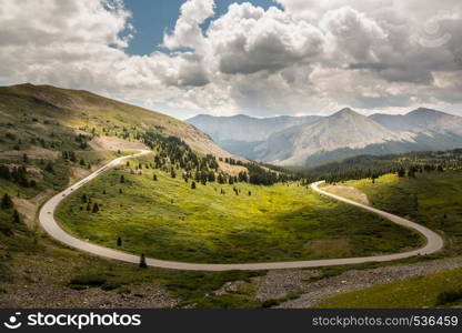 Large curving bend on road climbing to top of Cottonwood Pass in Colorado as sports cars race to summit. Large horseshoe bend on Cottonwood pass