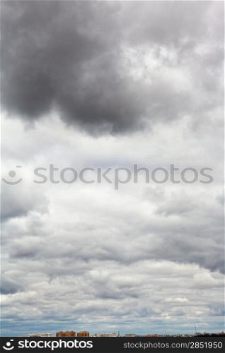 large dark rainy clouds under city in spring