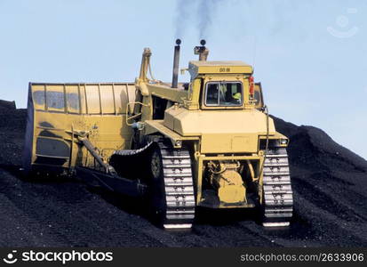 Large digging or bulldozing equipment moving large pile of earth