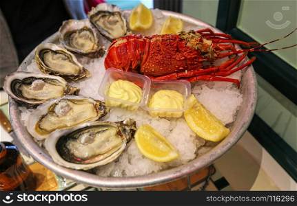 Large dish of fresh seafood, oysters with lobster with lemon and sauce on ice in a restaurant