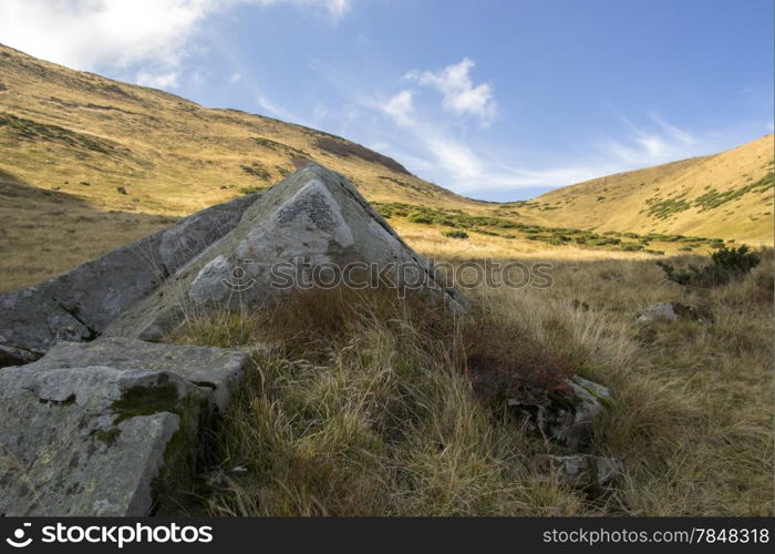 large gray stone in the mountains under the sky