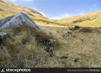 large gray stone in the mountains under the sky