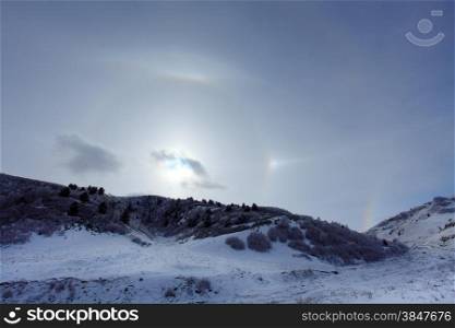 Large halo around the sun on a winter day in mountains. Hasaut village, North Caucasus, Russia.