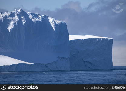 Large iceberg drifts in blue water from ocean in Antarctica