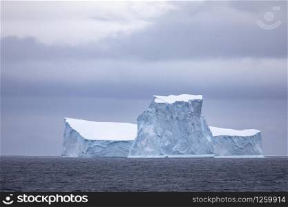 Large iceberg glistens blue through the cool landscape in Antarctica