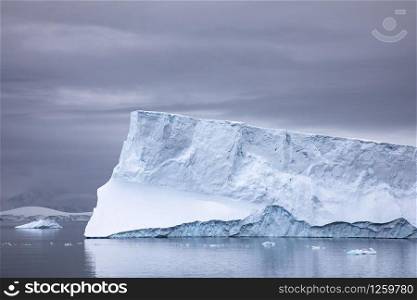Large iceberg glows with beautiful play of light on the calm sea of Antarctica