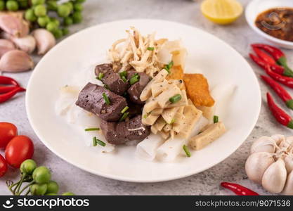 Large noodle noodles with pork blood sausage, crispy pork slices, and sliced ??onions in a white plate.