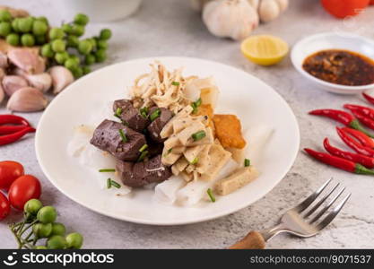 Large noodle noodles with pork blood sausage, crispy pork slices, and sliced   onions in a white plate.