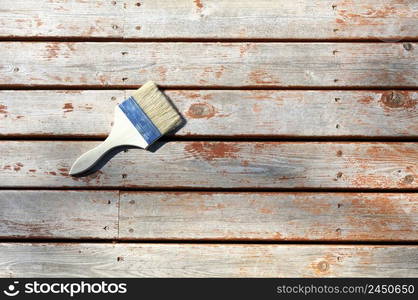 Large paint brush on top of cleaned cedar wood deck for staining purposes