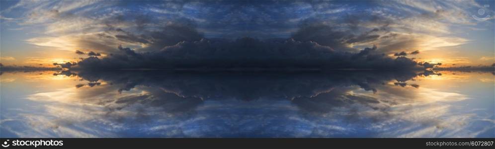 Large panorama image of stormy sunset sky reflected in still water