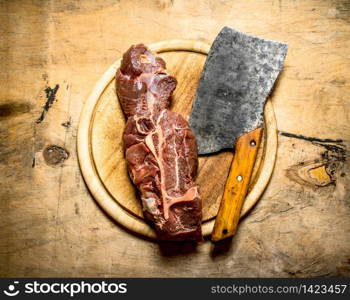 large piece of beef with a meat axe on the Board. On a wooden table.. large piece of beef