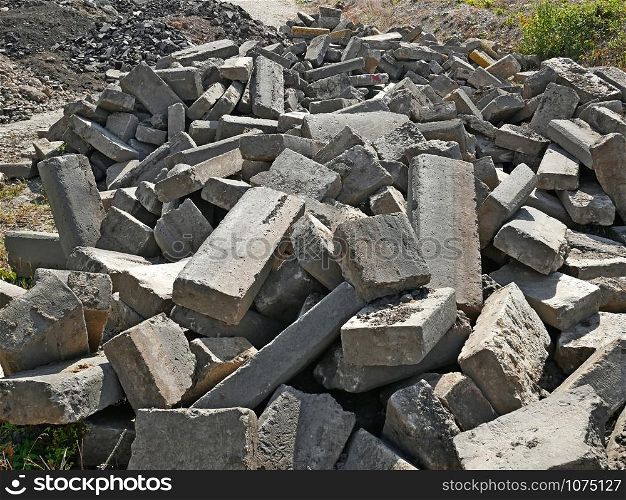 Large pile of old broken concrete blocks that were used in road pavement construction as a secondary raw materials