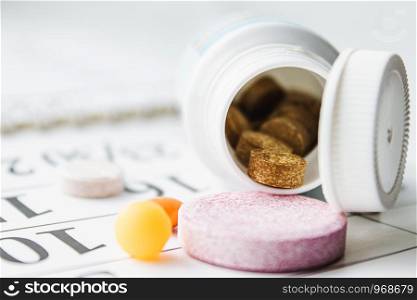 Large pink pills or vitamins near a jar on a calendar background. Healthcare. Large pink pills or vitamins near a jar on a calendar background.