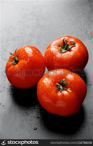 Large ripe red tomatoes with drops of water. Seasonal vegetables for a healthy diet. Large red tomatoes with drops of water. Seasonal vegetables for a healthy diet