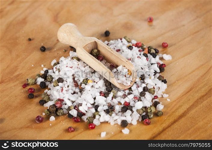 Large sea salt with red and black pepper. Large sea salt with red and black pepper with a small wooden spoons on a beautiful wooden tray .