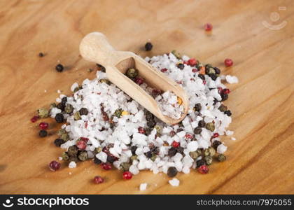 Large sea salt with red and black pepper. Large sea salt with red and black pepper with a small wooden spoons on a beautiful wooden tray .